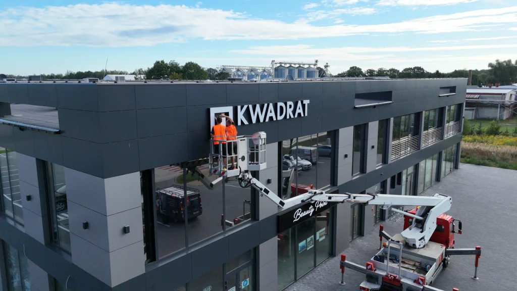 Montaż podświetlanego napisu KWADRAT na elewacji budynku