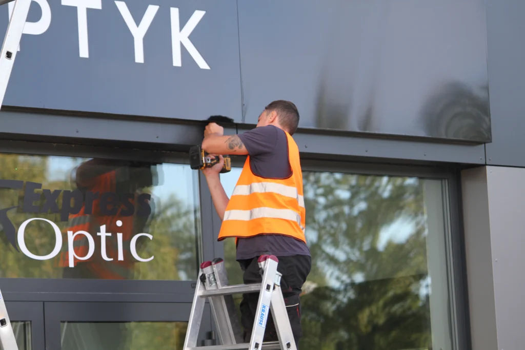 Montaż dużego kasetonu reklamowego na budynku usługowym KWADRAT